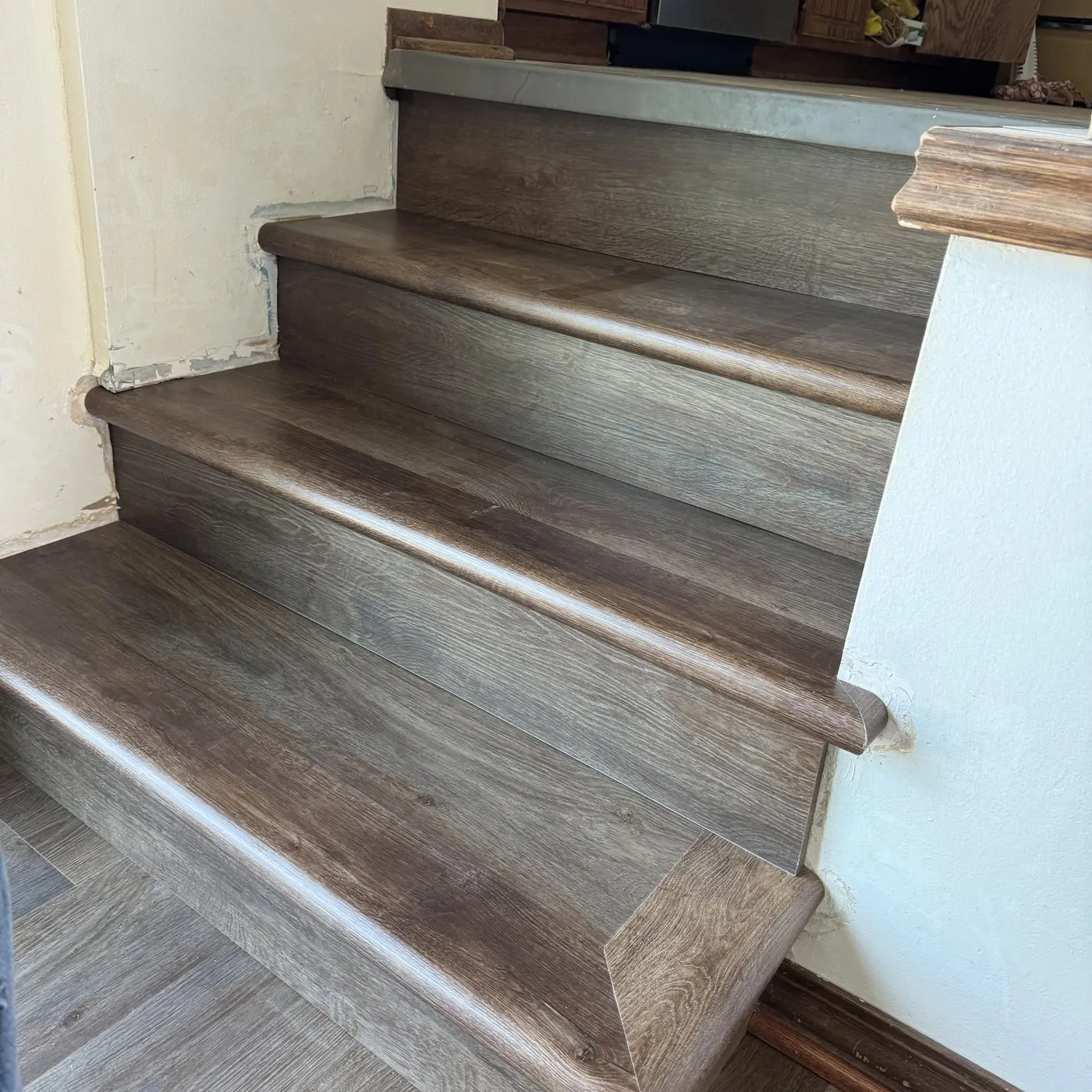 Staircase with new gray-brown plank flooring wrapped over each tread and riser
