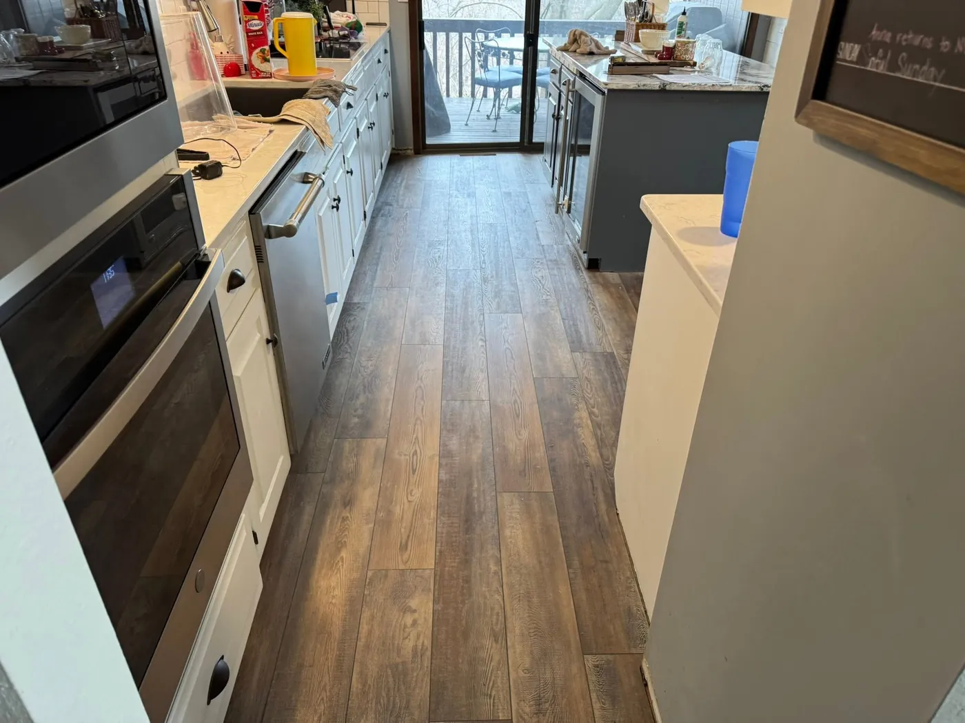 Narrow kitchen with new dark plank flooring running past the oven and counters