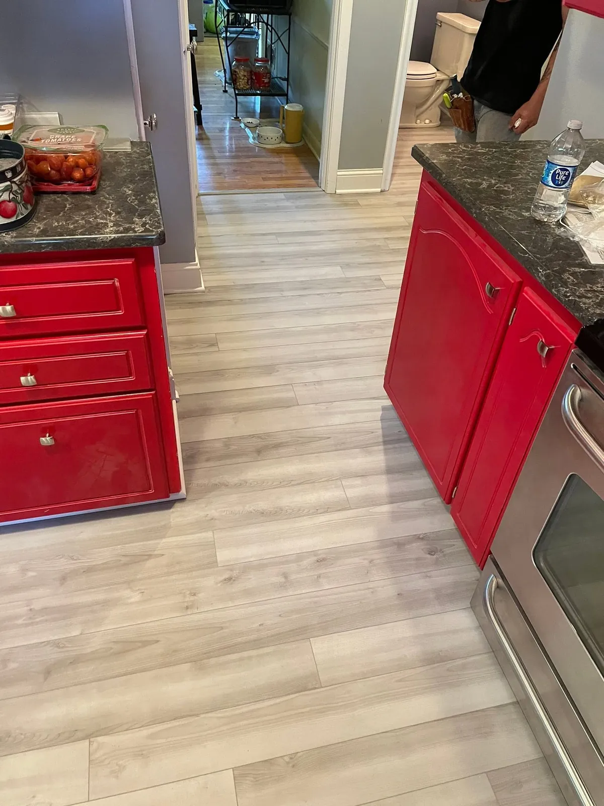 Kitchen with red cabinets and a freshly installed light gray plank floor